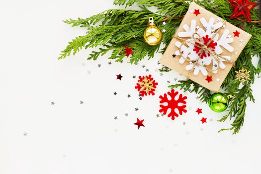 Christmas and New Year background with thuja branch, decorations and present wrapped in craft paper with snowflakes. Flat lay, top view. Place for text.