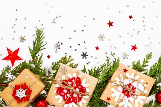Christmas and New Year background with thuja branch, decorations and presents wrapped in craft paper with snowflakes. Flat lay, top view.