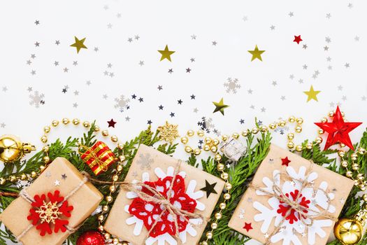 Christmas and New Year background with thuja branch, decorations and presents wrapped in craft paper with snowflakes. Flat lay, top view.