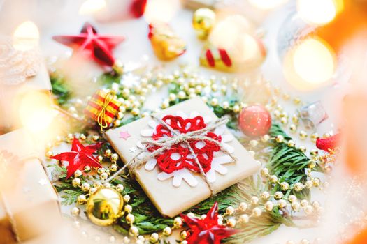 Christmas and New Year background with thuja branch, decorations and presents wrapped in craft paper with snowflakes.