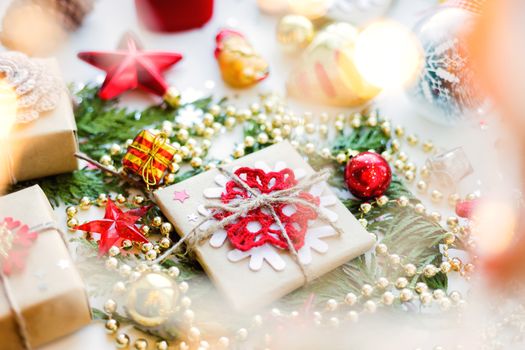 Christmas and New Year background with thuja branch, decorations and presents wrapped in craft paper with snowflakes.