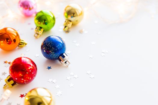 Christmas and New Year background with colorful decorative balls for Christmas tree with light bulbs and confetti. Place for text.