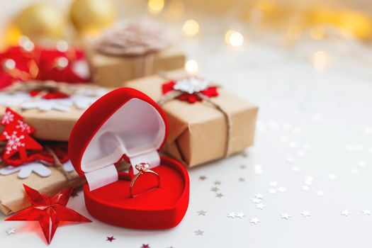 Christmas and New Year background with engagement ring and presents, decorations for Christmas tree. Holiday background with stars confetti and light bulbs. Place for text.