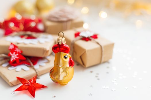 Christmas and New Year background with rooster, symbol of 2017 year, presents and decorations for Christmas tree. Holiday background with stars confetti and light bulbs. Place for text.