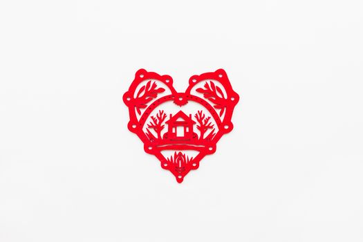 Wooden heart with silhouette of house. Ornamental red Christmas and New Year decoration. Top view, flat lay on white background.