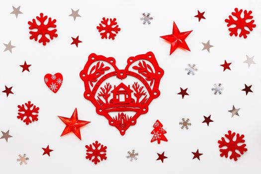 Christmas and New Year holiday background with decorations. Red heart with home symbol, snowflakes and star confetti. Flat lay, top view.