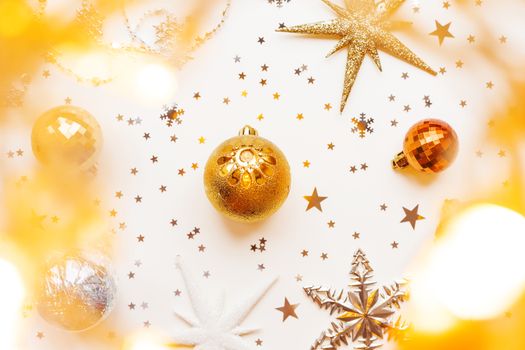 Christmas and New Year holiday background with decorations and light bulbs. Silver and golden shining balls, snowflakes and star confetti. Flat lay, top view.