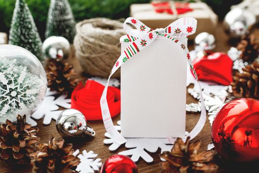 Christmas and New year background with presents, ribbons, balls and different red decorations on wooden background. White present with ribbon and clear surface for your text. Mock up.
