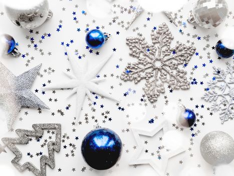 Christmas and New Year background with decorations - shiny stars, balls, snowflakes, confetti and light bulbs.