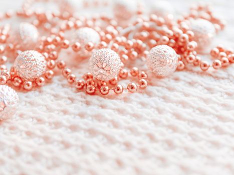 Christmas and New Year decorations on white knitted background. Metal light bulbs with delicate pattern, light red beads.