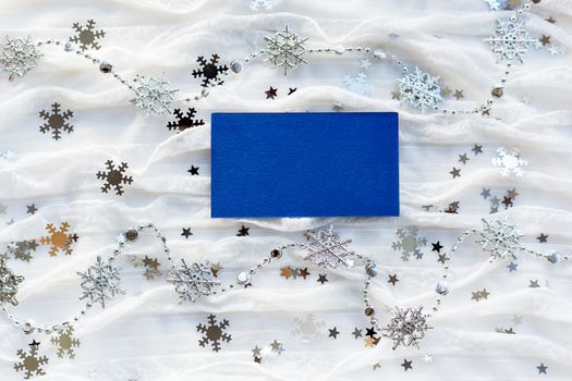 Winter background with decorative sparkling snowflakes and empty piece of blue paper for your text.