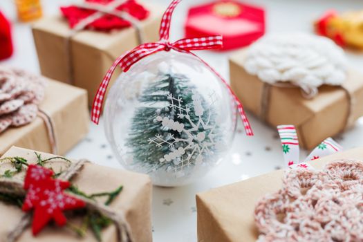 Christmas and New Year background with presents, decorations and transparent decorative ball with fir tree inside.
