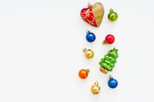 Christmas background with decorations. New Year symbol - fir tree. Shiny colorful balls and red heart. Flat lay, top view. Place for text.