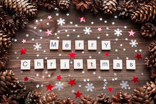 Rustic wooden background with pine cones. Merry Christmas background with bright snowflake confetti.