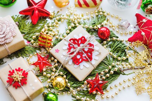 Christmas and New Year background with thuja branch, decorations and presents wrapped in craft paper with snowflakes.