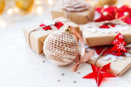 Christmas and New Year background with crocheted handmade ball, presents and decorations for Christmas tree. Holiday background with stars confetti and light bulbs. Place for text.