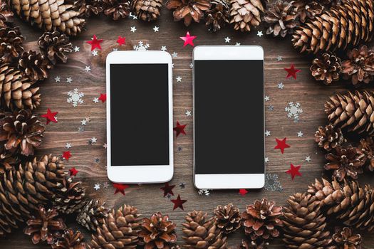 Rustic wooden background with two smartphones and Christmas decorations. Mock up, top view, flat lay. Place for text.