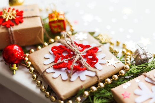 Christmas and New Year background with thuja branch, decorations and presents wrapped in craft paper with snowflakes.