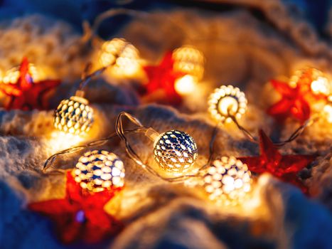 Christmas and New Year knitted background with light bulbs and red stars. Cozy holiday decorations.