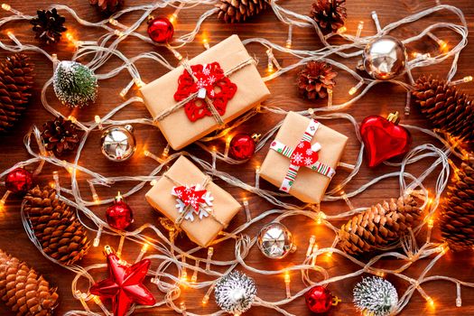 Christmas and New Year background with christmas decorations - balls, star, silver sparkling snowflakes, heart and light bulbs on wooden table.