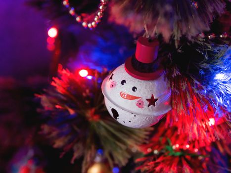 Funny snowman ball on Christmas tree. Colorful light bulbs and decorations on traditional fir tree for New Year celebration.