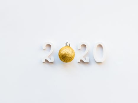 New Year 2020 background with golden ball. Numbers 2020 on white copy space with decorative ball for Christmas tree.