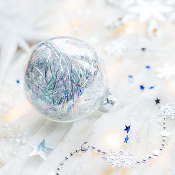 Christmas and New Year holiday background with decorations and light bulbs. Silver and blue shining balls, snowflakes and star confetti.