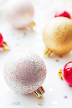 Christmas and New Year background with golden and red decorative balls for Christmas tree with light bulbs and confetti.