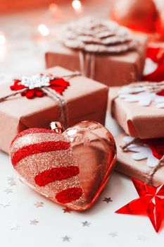 Christmas and New Year background with presents and decorative heart for Christmas tree. Holiday background with stars confetti and light bulbs.