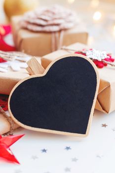 Christmas and New Year background with heart chalkboard, presents and decorations for Christmas tree. Holiday background with stars confetti and light bulbs. Place for text.
