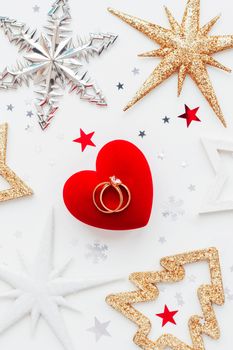 Christmas and New Year holiday background with decorations and wedding rings on gift heart box. Top view, flat lay.