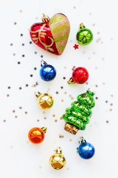 Christmas background with decorations. New Year symbol - fir tree. Shiny colorful balls, heart and confetti. Flat lay, top view. Place for text.