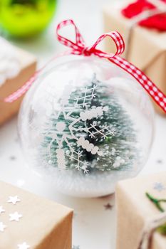 Christmas and New Year background with presents, decorations and transparent decorative ball with fir tree inside.
