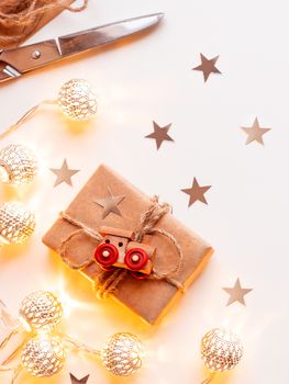 Wrapped DIY presents in craft paper. Gift tied with rustic thread with toy train as decoration. Metal light bulbs with delicate pattern. Place for text.