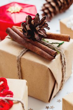 Christmas and New Year background with presents and decorations. Hand made gift wrapped in craft paper with pine cone and cinnamon.
