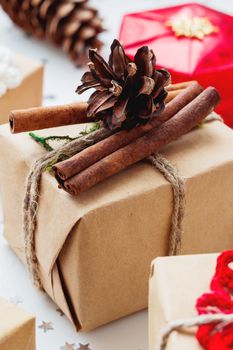 Christmas and New Year background with presents and decorations. Hand made gift wrapped in craft paper with pine cone and cinnamon.