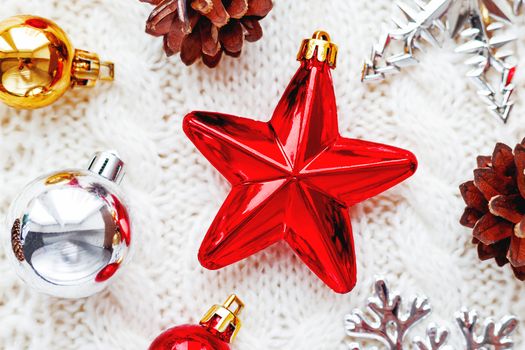 Christmas and New Year background with decorations - balls, star, silver sparkling snowflakes on knitted fabric with decorative pattern.