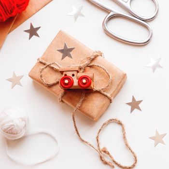Christmas and New Year DIY presents in craft paper. Holiday gifts tied with white and red threads with toy train as decoration.