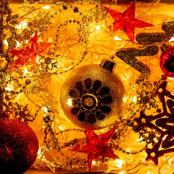 Cardboard box with Christmas and New Year decorations and light bulbs. Little baby touching red sparkling snowflake.