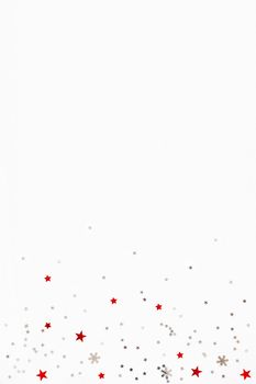 Christmas and New Year background with sparkling red and silver stars confetti. Flat lay, top view. Place for text.