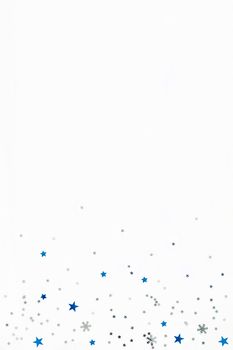 Christmas and New Year background with sparkling blue and silver stars confetti. Flat lay, top view. Place for text.