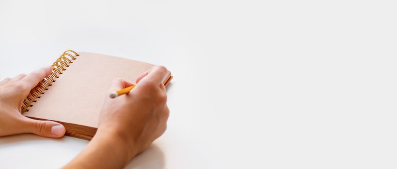 Woman is preparing to write or draw something in notepad with craft paper pages. Banner with copy space.