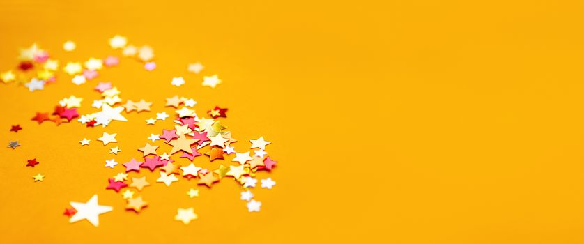 Yellow holiday background with colorful star confetti. Good background for Christmas and New Year cards.