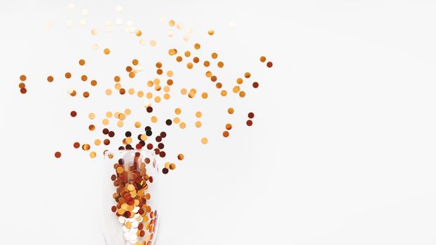 Transparent wine glass with golden spangles. Festive copy space with crockery on white background.