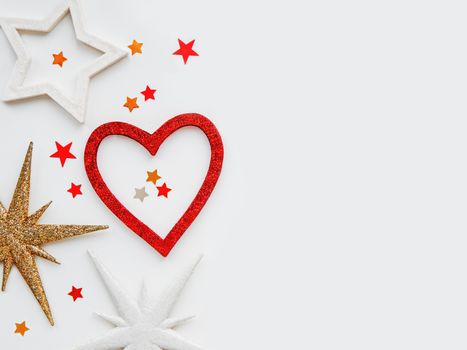 Christmas and New Year background with sparkling red heart and star confetti. Holiday symbols on white background.