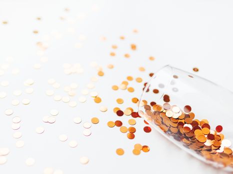 Transparent wine glass with golden spangles. Festive copy space with crockery on white background.