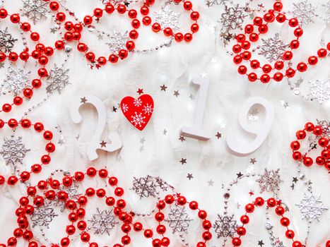 Christmas and New Year background with numbers 2019, red heart, silver decorations and light bulbs.