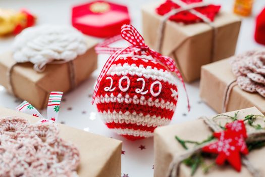 Christmas and New Year 2020 background with presents, decorations and crocheted handmade decorative ball.