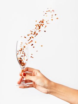 Woman holding transparent wine glass with golden spangles. Festive copy space with crockery on white background.