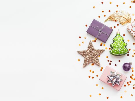 Christmas and New Year 2020 background with decorations. Green fir tree, golden feathers, presents and stars confetti.